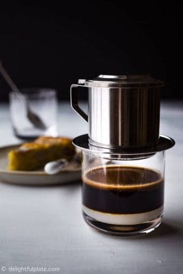 “Ly cà phê Oni nóng hổi trên bàn gỗ.”